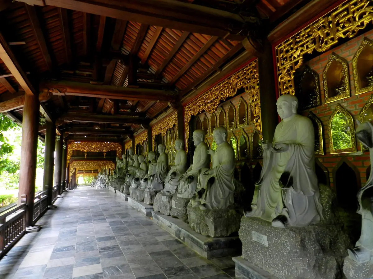 Wooden covered corridor lined with stone statues of arhats