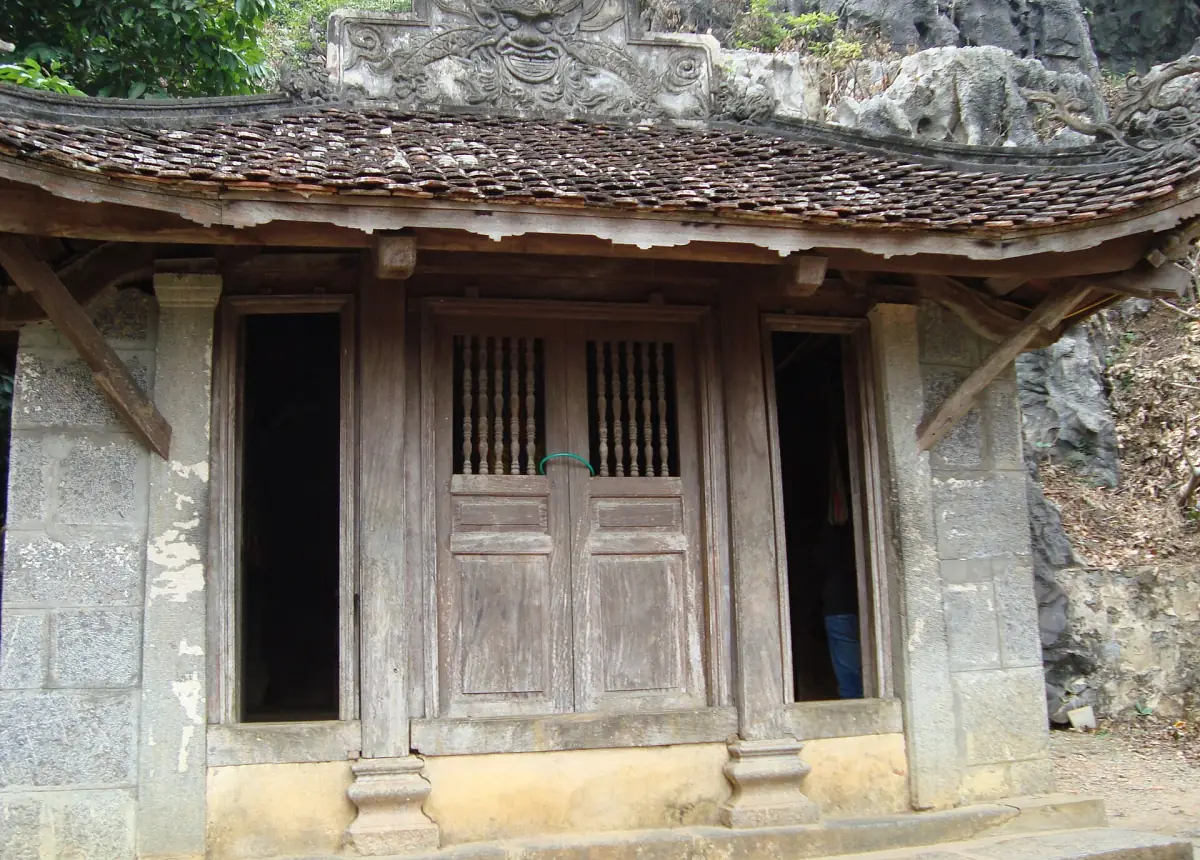 Old wooden temple building set against a rock face