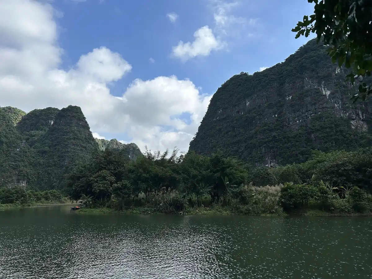 Limestone peaks and a still river under blue sky with clouds