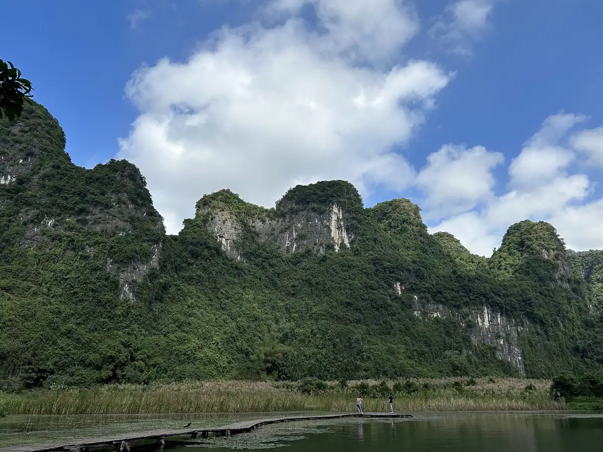 Forested limestone ridge under a blue sky with white clouds
