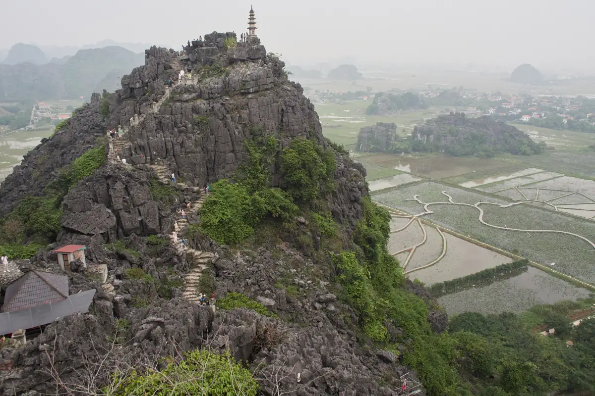 Rocky ridge with a small pagoda on top above rice paddies