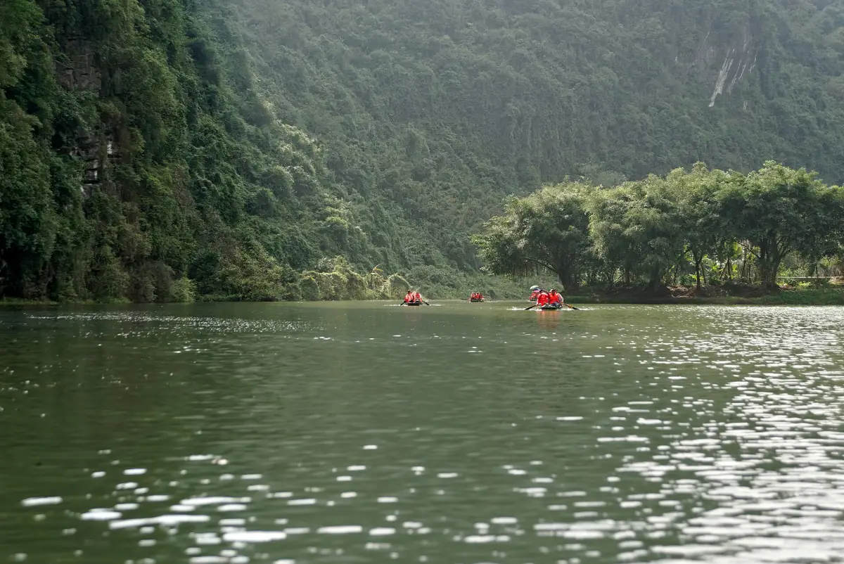 Wide river with distant boats beneath steep green cliffs