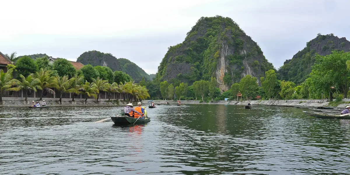 Rowing boat on the Ngo Dong River with limestone hills and palms