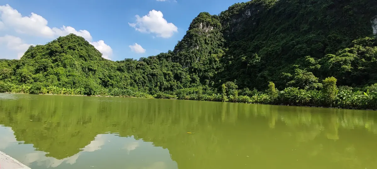 Calm green lake reflecting forested limestone hills