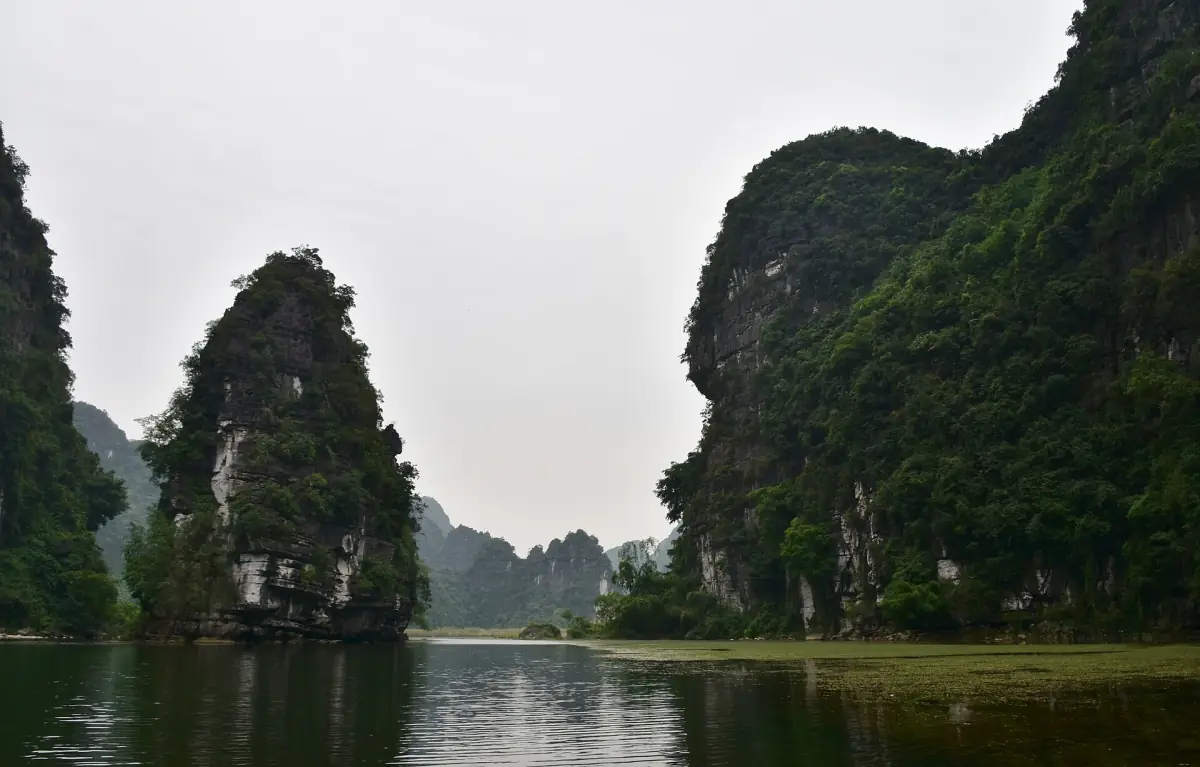 River winding between two steep limestone peaks under hazy sky