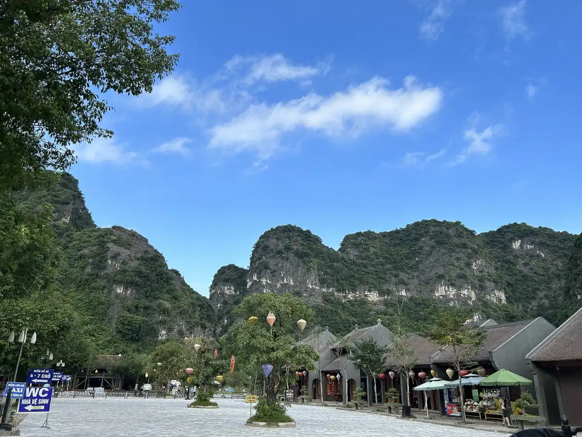 Paved path with village huts and limestone peaks under a blue sky