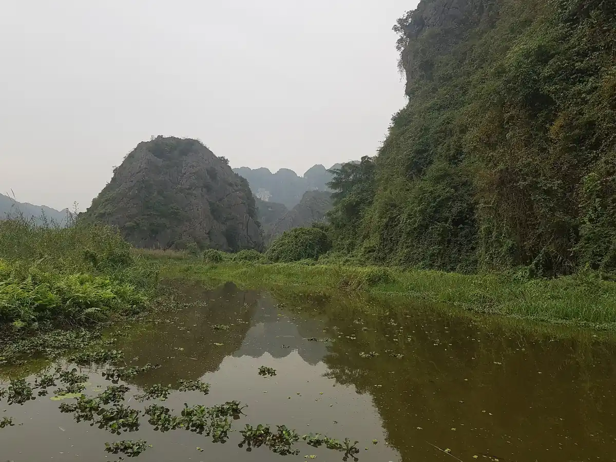 Still wetland water reflecting a limestone hill and green slopes